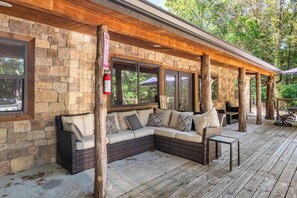 A covered outdoor seating area with stone walls, wooden beams, and a stone fireplace. - Pottsboro Lodge - Sleeps 15 - Hot Tub & Patio (Pottsboro)