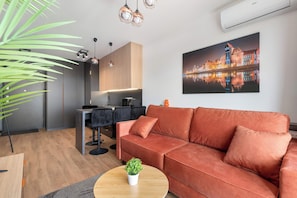 A modern living room with a sofa, a dining area, and a kitchen. - Modern Apartments with Balconies | Downtown (Gdańsk)