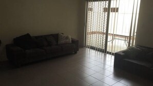 Una sala de estar con un sofá, un sillón adicional y un ventanal corredero que da a un espacio exterior.