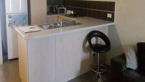 Cocina compacta con un lavamanos, un microondas y un refrigerador.