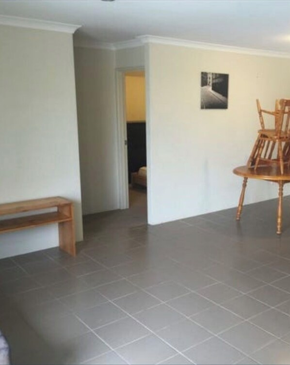 A room with a bench, a wooden chair, and a tiled floor.