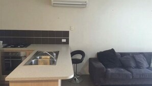Una cocina con isla integrada, un sofá oscuro y un aire acondicionado de pared.