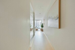Ein Flur mit modernem Interieur, einem großen Fenster und einem gerahmten Kunstwerk an der Wand.