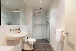 A modern bathroom with a sink, toilet, and glass-enclosed shower. - Newly Refurbished 1 BDR CBD Studio on Liverpool St (Melbourne)