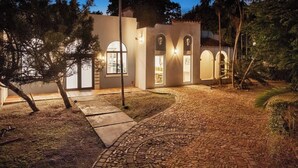 Ein modernes Haus mit befestigter Auffahrt, gewölbten Fenstern und einem gut beleuchteten Eingang.