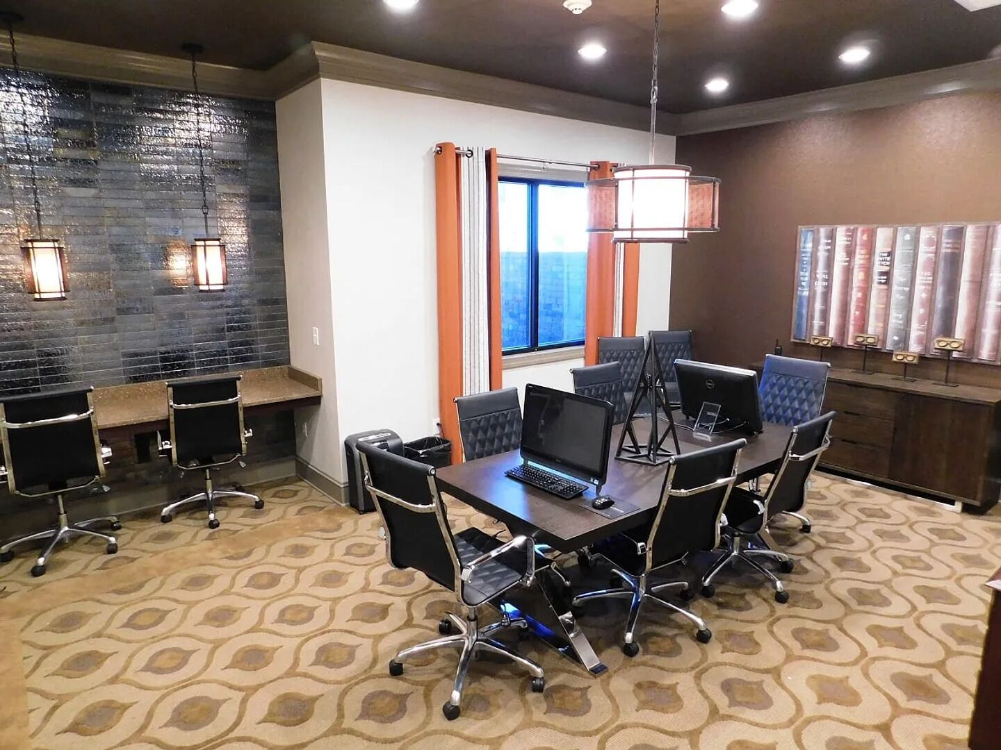 A conference room with a long table, multiple chairs, laptops, and a large window with curtains.