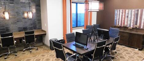 A conference room with a long table, multiple chairs, laptops, and a large window with curtains.