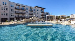 A swimming pool with lounge chairs and a building with balconies in the background. - Landing Beautiful 1bd, Yoga Studio (San Antonio)