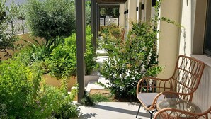 Un’area esterna coperta con mobili in vimini, un vialetto e vegetazione.