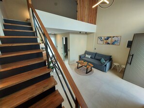 Ein modernes Wohnzimmer mit Treppe, Sofa, Couchtisch und Essbereich.