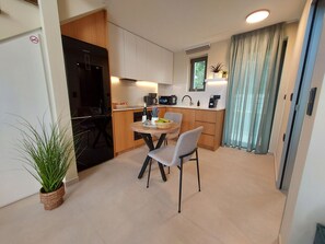 Una cocina compacta con comedor, un refrigerador, una cafetera y una planta en maceta.
