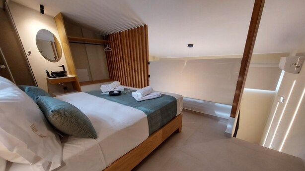 Een moderne hotelkamer met een bed, nachtkastje, spiegel en uitzicht.
