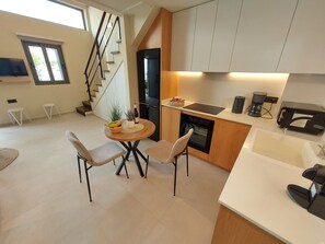 A modern kitchen with a dining area, a staircase, and a view of the outdoors. - Elea Suites - Olive - Adelianos Kampos (Adelianos Kampos)
