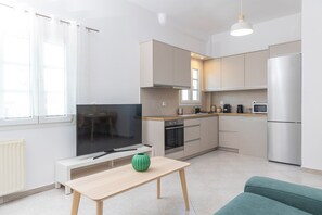 A modern kitchen with a dining area, a TV, and a sofa. - Grafeio - Two-Bedroom Deluxe Apartment wt Balcony (Naxos)