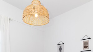 Et moderne soveværelse med en seng, en hængende lampe og to billeder på væggen.
