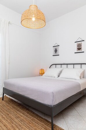 Ein modernes Schlafzimmer mit einem Bett, einer hängenden Leuchte und zwei Bilderrahmen an der Wand.