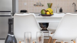 Et moderne køkken med spiseplads, med et hvidt bord, stole og en skål med frugt på disken.