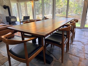 A large wooden dining table with matching chairs, a stone floor, and a view of a forest through large windows. - Spacious private modern 4-bedroom house in beautiful natural setting in Brooklin (Brooklin)