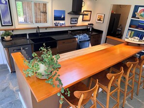 A kitchen with a wooden island, chairs, a stove, and a coffee maker. - Spacious private modern 4-bedroom house in beautiful natural setting in Brooklin (Brooklin)