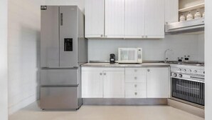 A kitchen with white cabinets, a stainless steel refrigerator, a microwave, and a stove. - Hostdomus - Queen Suite (Marina di Andora)
