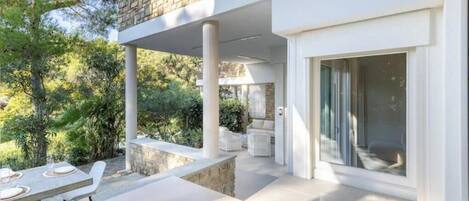 A modern house with a patio, a dining area, and a large glass door.