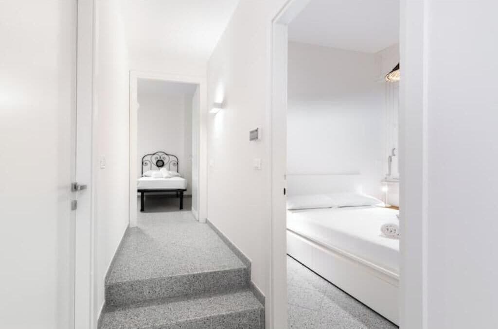 A modern hotel room with a bed, a bedside table, and a small seating area.