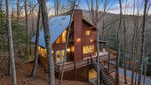 Une cabane avec une façade en bois, un balcon et un escalier menant à un étage supérieur.
