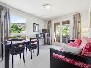 A room with a dining table, chairs, a TV, a sofa, and a balcony with a view. - Flat with a swimming pool and a balcony with mountain views (Grasse)