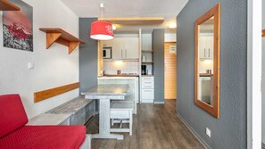 A compact kitchen with white cabinets, a wooden bench, and a red hanging light fixture. - Charming Studio - Sleeps 4 - Right at the Foot of the Slopes (Tignes)