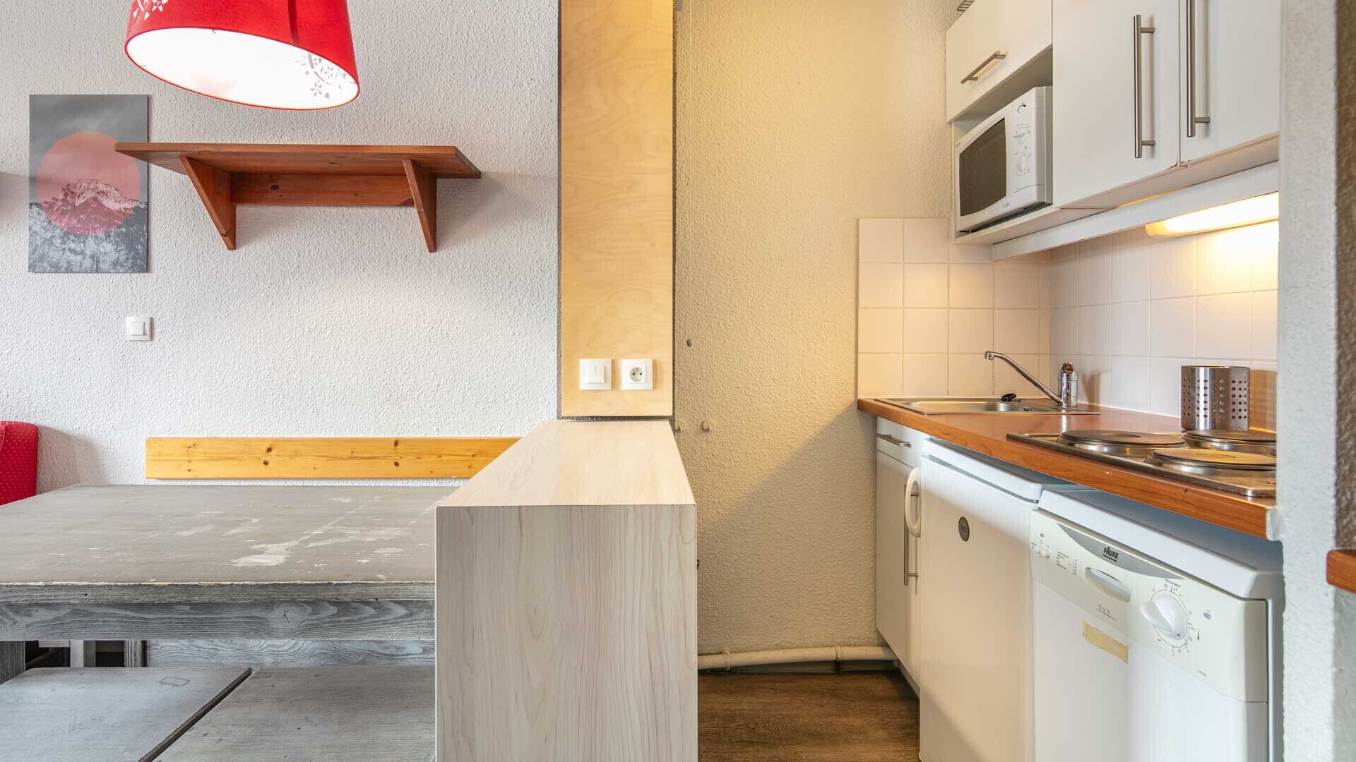 Eine kleine Küche mit Holzarbeitsplatte, weißen Schränken, einer Mikrowelle und einem Spülbecken.