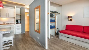 A compact living space with a kitchenette, a mirrored wardrobe, a red sofa, and a small table. - Charming Studio - Sleeps 4 - Right at the Foot of the Slopes (Tignes)