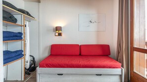 A compact room with a bed, a wardrobe, a wall-mounted lamp, and a framed picture. - Charming Studio - Sleeps 4 - Right at the Foot of the Slopes (Tignes)