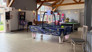 Ein großzügiger Innenbereich mit Billardtisch, Spielautomaten und einem Sessel.