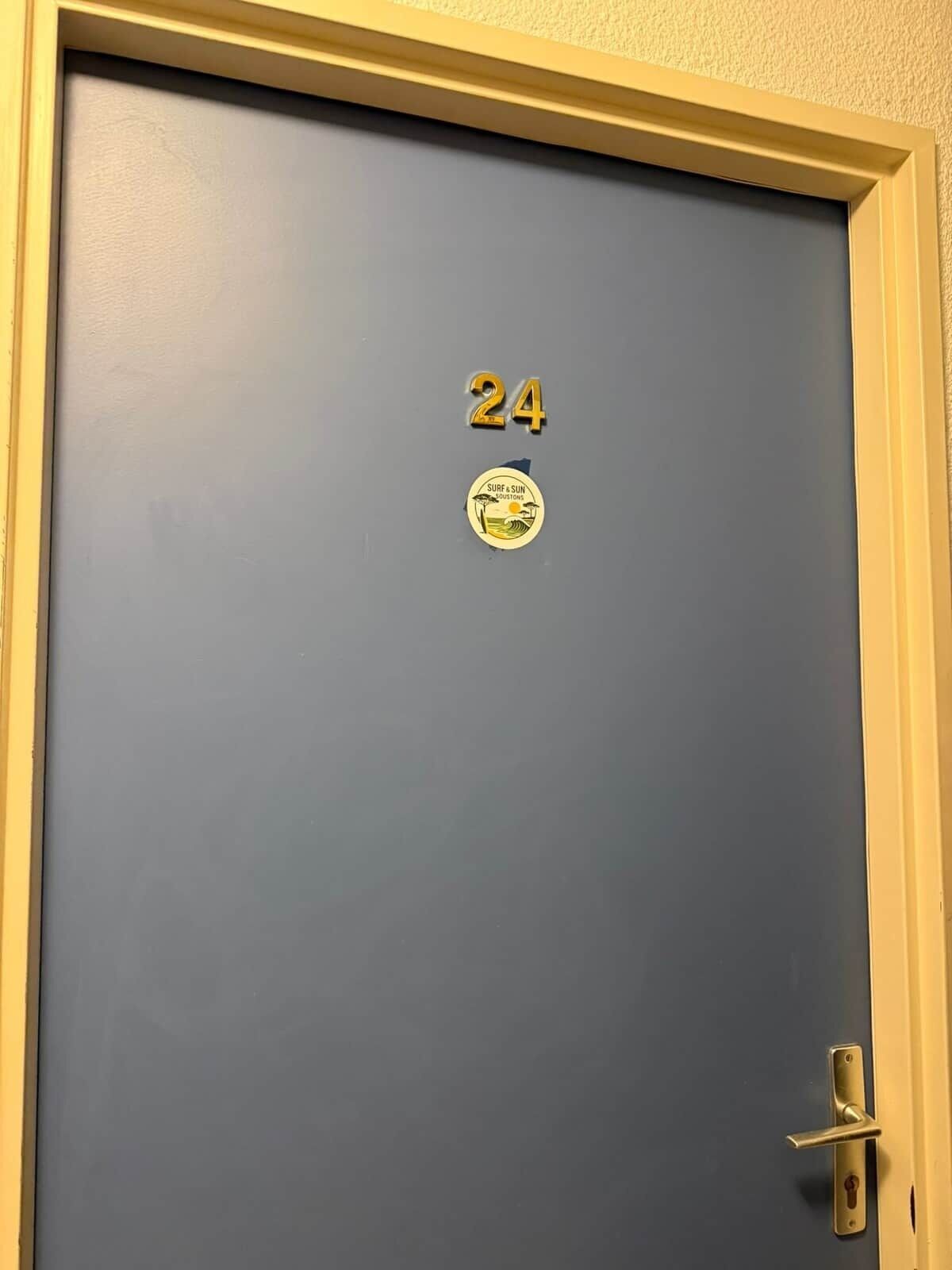 A blue door with the number 24 and a sticker that reads 'Surf & Sun Resorts.'