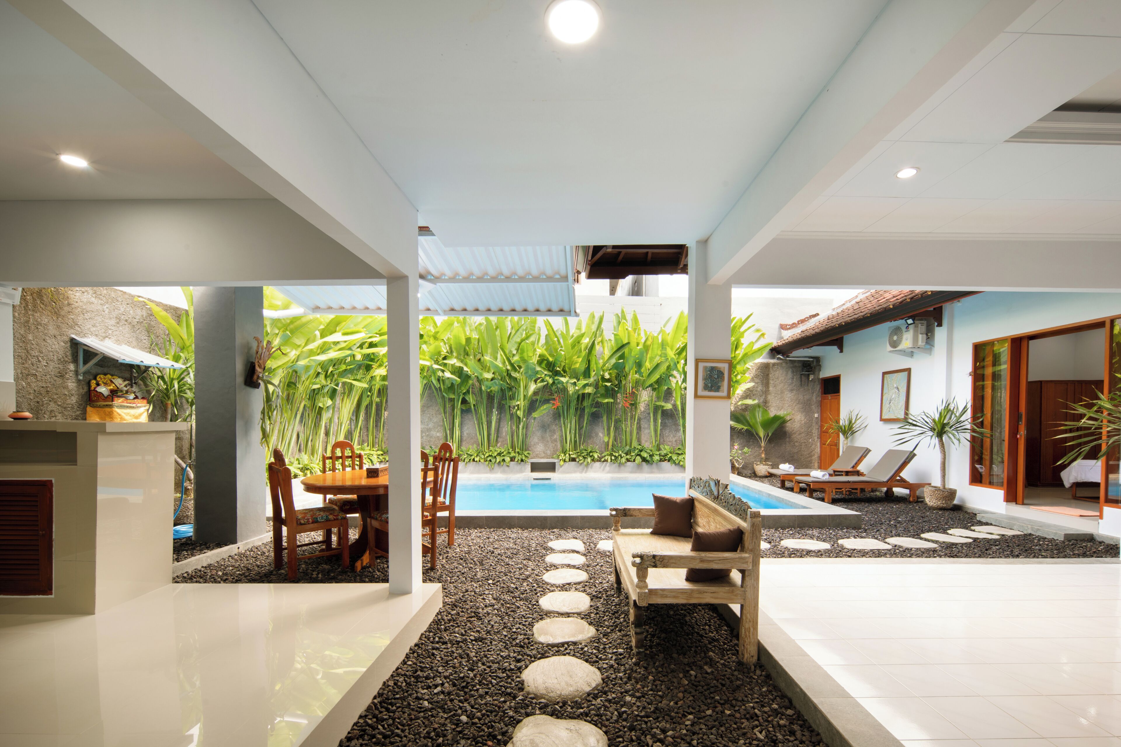 Un área moderna de piscina interior con un sendero de piedra, asientos y vistas a vegetación exuberante.