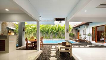 Un área moderna de piscina interior con un sendero de piedra, asientos y vistas a vegetación exuberante.