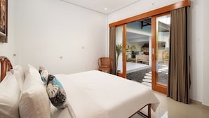 Una habitación de hotel con una cama, una silla, una puerta corrediza de vidrio a un espacio exterior y un cuadro en la pared.