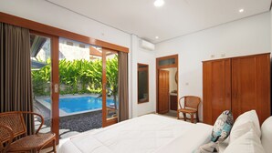 Un dormitorio con una cama grande, una silla, un armario y vistas a una piscina.