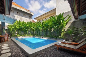 Una piscina al aire libre, sillones reclinables de piscina