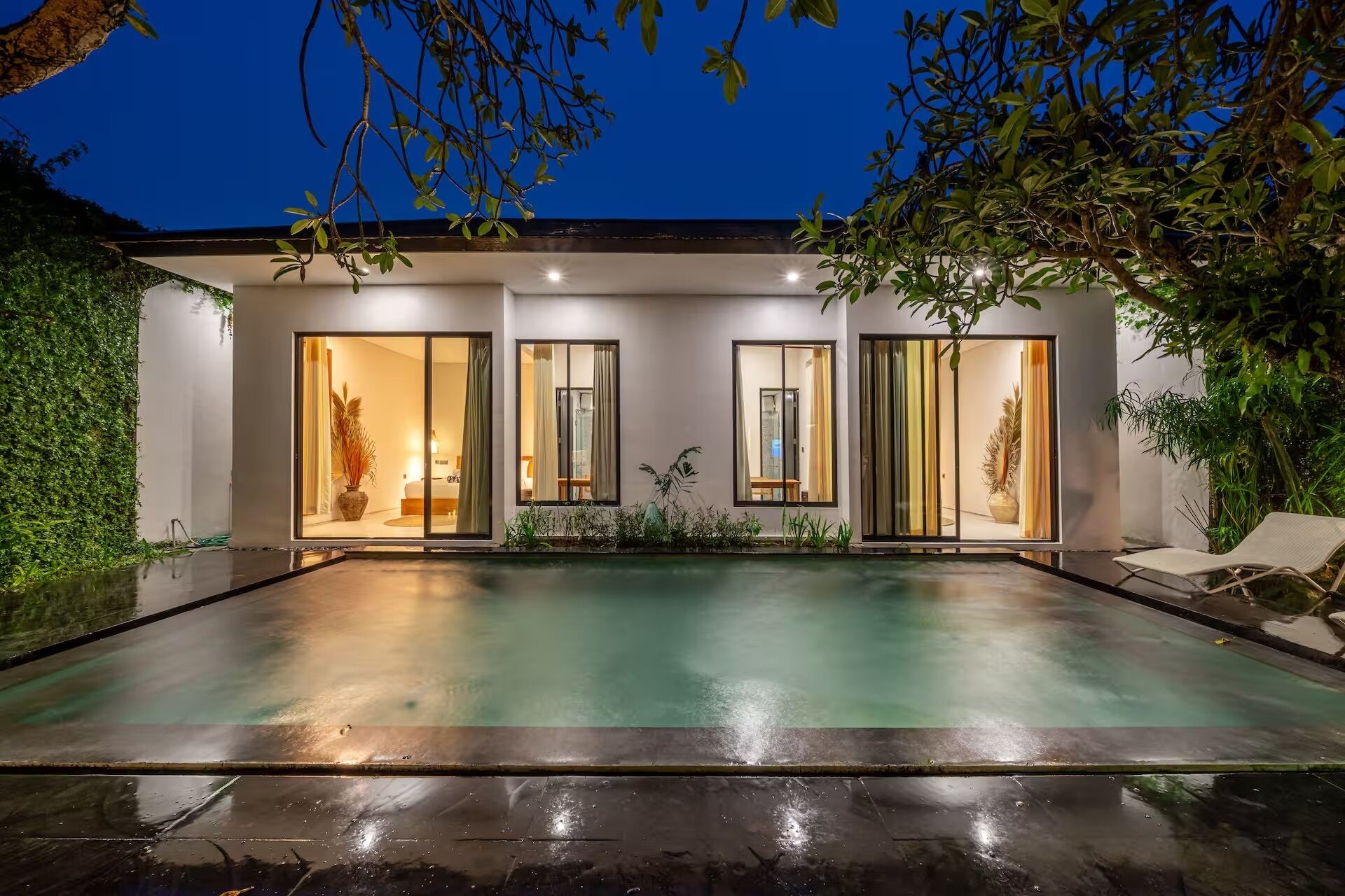 A modern house with a swimming pool, large windows, and a garden.
