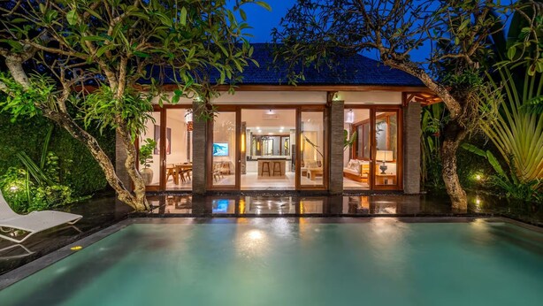 A modern house with a swimming pool, glass doors, and a well-lit interior. - Mimosa villa (Kerobokan)