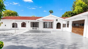 A white building with a red-tiled roof, multiple windows, and a large garage door. - Room-tranquil Studio Retreat With Pool a (Westville)