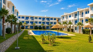 Ein Hotel mit Swimmingpool, Palmen und blauem Himmel.