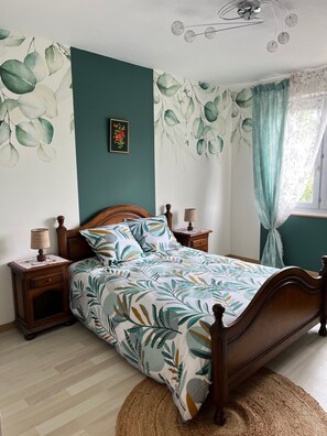 A bedroom with a bed, wooden nightstands, a lamp, a ceiling fan, and a window with curtains. - Pont-Aven vacation home, ideal for families. Pets welcome! (Pont-Aven)