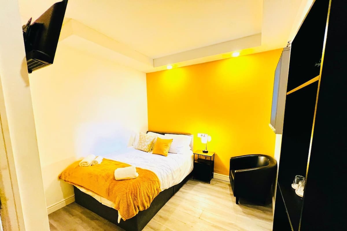 A bedroom with a bed, bedside table, and a chair.
