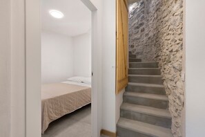 A bedroom with a bed, a wooden door, and a stone staircase.