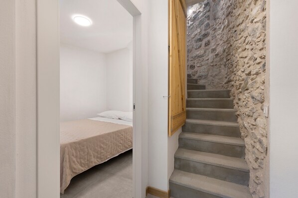 Une chambre à coucher avec un lit, une porte en bois et un escalier en pierre.