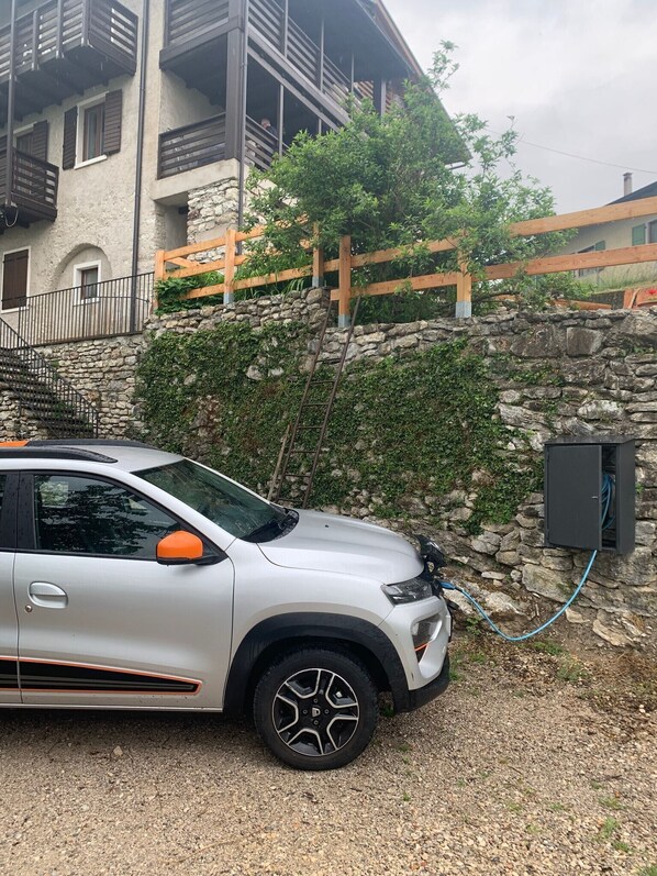 A white SUV parked in a driveway with a stone wall and wooden fence. - Casa Zucchelli, Garda Trentino: Castle View, Private Garden, Up to 8 Guests (Pranzo)