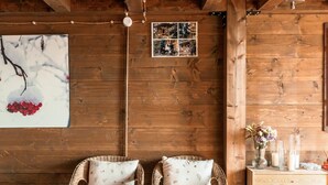 Un intérieur en bois avec deux fauteuils en osier, une commode en bois et un tapis à motifs.