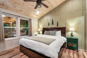 Ein Schlafzimmer mit einem großen Bett, Holzboden und Blick durch eine Schiebetür.
